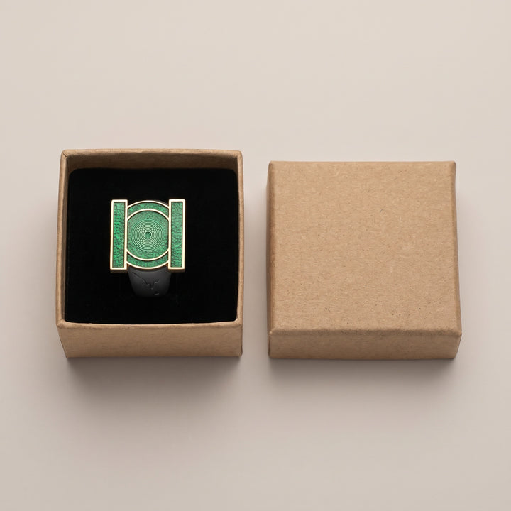 Green emblem copper ring displayed in its included kraft box with black insert