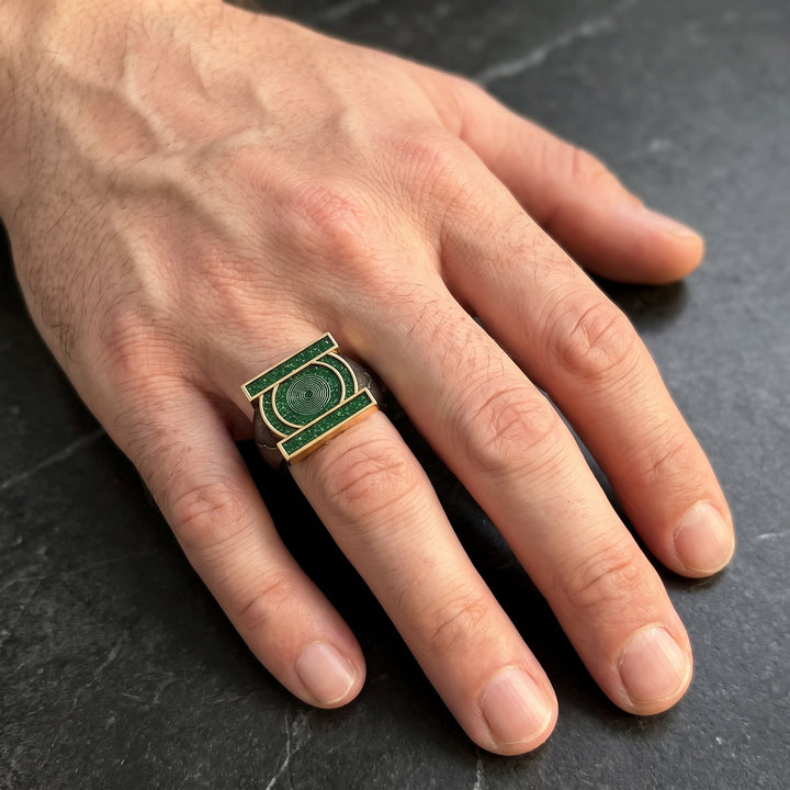 Green emblem copper open ring worn on a male hand with light skin